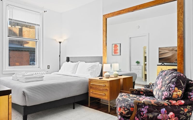 Minimalist bedroom with large mirror and floral armchair