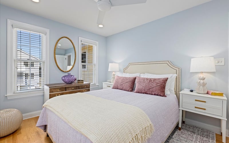 Soft blue bedroom with pink pillows and oval mirror